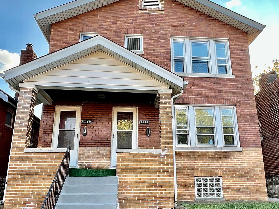 Front of building, all brick with red front doors, a front patio and new steps