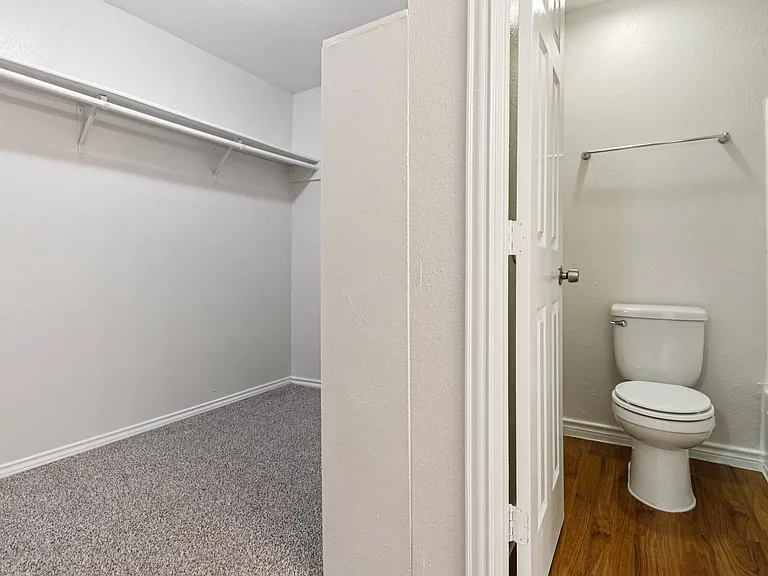 Spacious apartment featuring a large walk-in closet next to a modern bathroom with wood-style flooring. Spacious apartment featuring a large walk-in closet next to a modern bathroom with wood-style flooring.