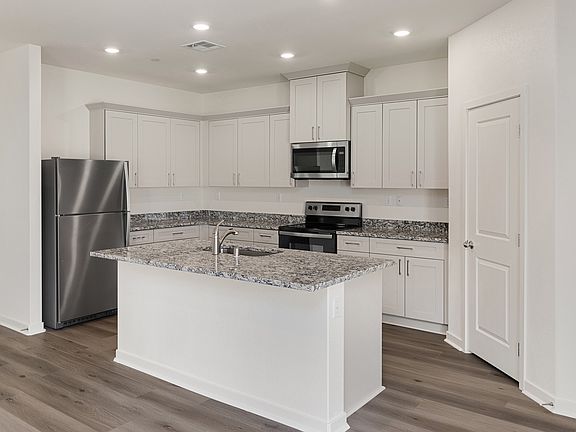 The kitchen has beautiful quartz counters and white cabinets.
