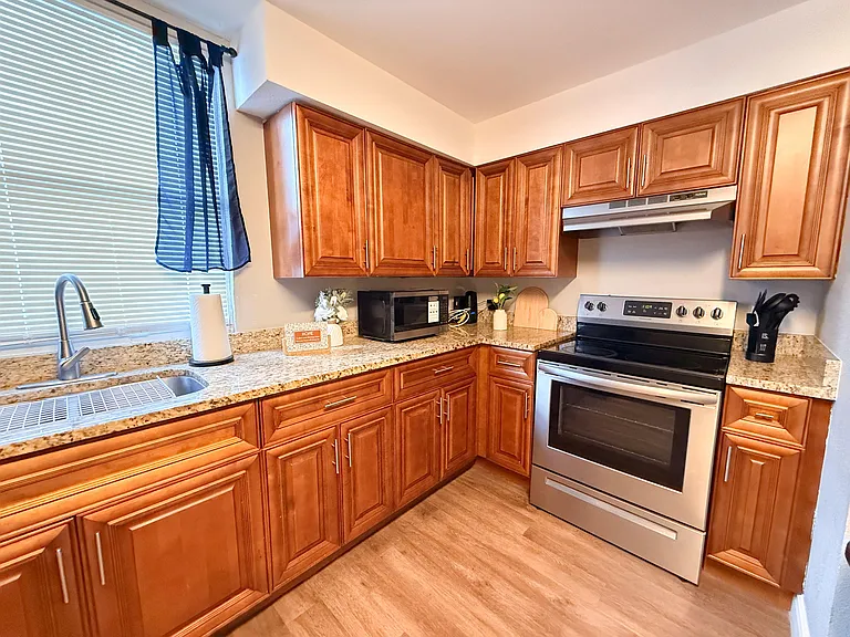 Functional kitchen with abundant wood cabinetry, granite-look counters, stainless range, and a window over the sink.