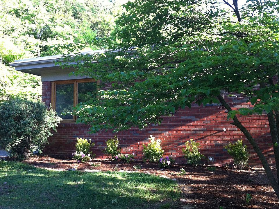 House sits far off the road and is nestled among trees.