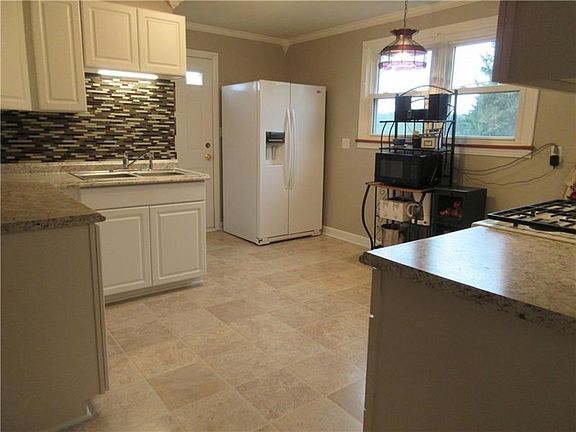 The updated kitchen is shining with its new appliances, white cabinets and counters, and stunning glass back splash.