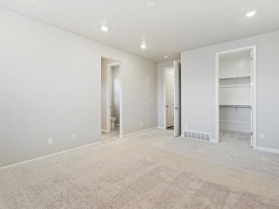 A view of the primary bedroom with doors to the bathroom and hallway