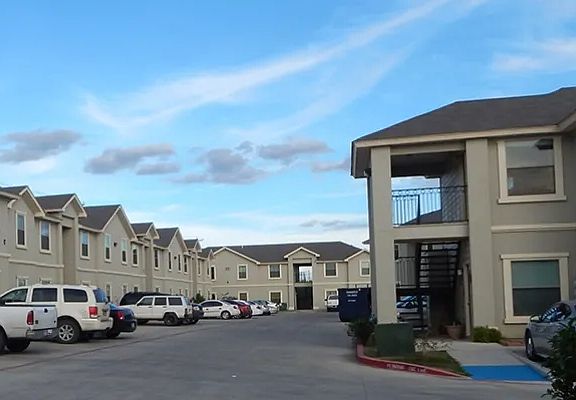Exterior Apartment Buildings with Parked Cars and Truck Cloudy Skies View - La Joya Apartments in Laredo Texas