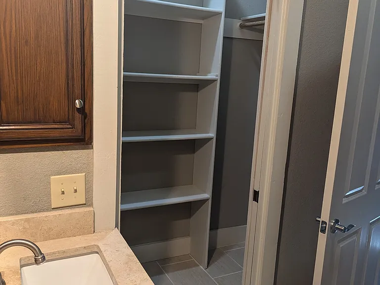 Walk in closet with built in shelves and 3 hanging rods.