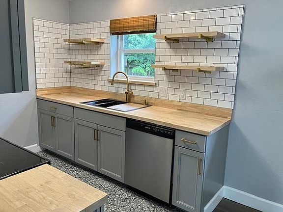 Updated kitchen with butcher block counters, open shelves, large sink, dishwasher