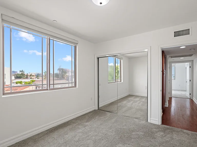 Bedroom with a Carpet, Window, and a Mirrored Closet