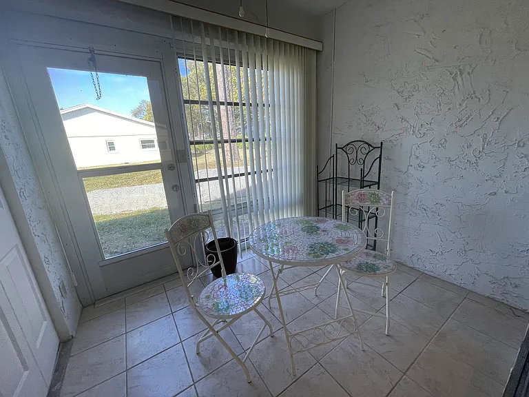 This is the Florida room which is off the living room. The washer and dryer are behind the louvered doors. The blinds can be pulled across the back wall to give you complete privacy if needed.