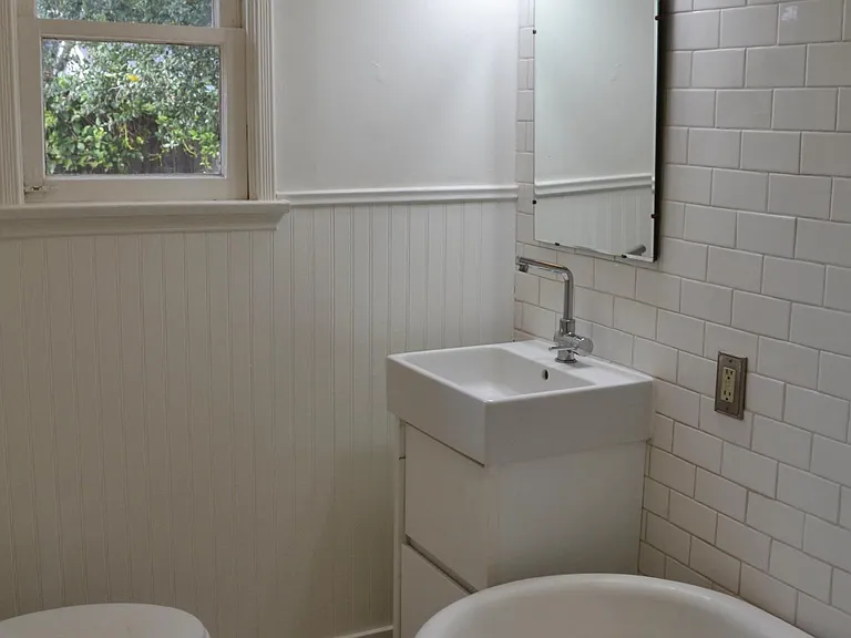Bathroom with clawfoot tub, wainscoting and subway tile on walls.