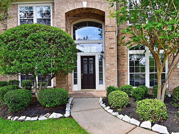 The mature landscaping leads up to a lovely wood door with glass inserts.
