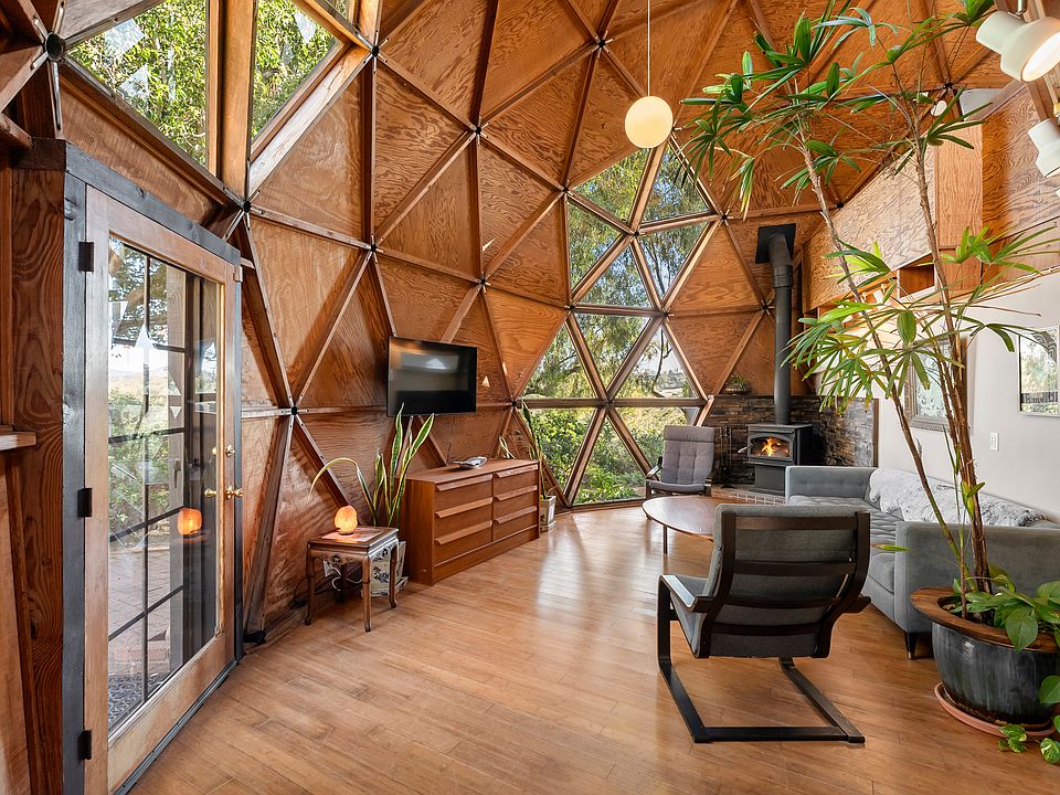Stunning geodesic dome living room with soaring wood ceilings, panoramic windows, and abundant natural light.