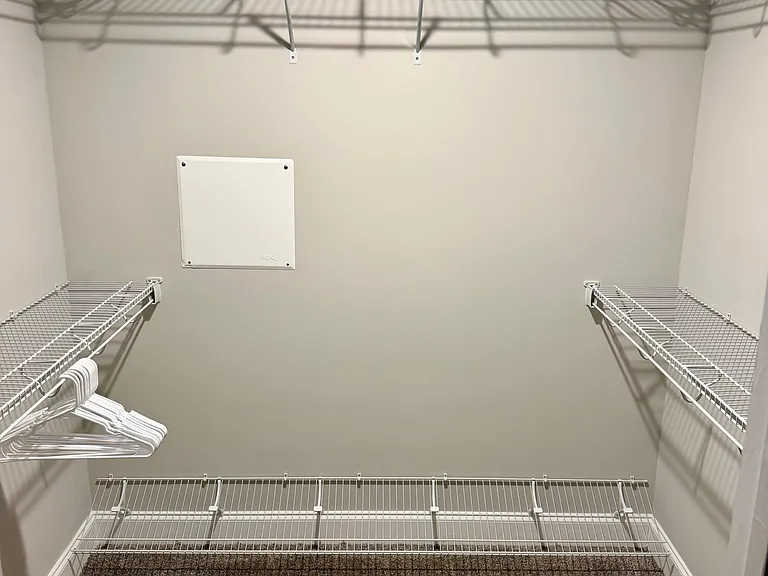 Spacious walk-in closet with wraparound wire shelving and hanging space to keep clothing, shoes, and storage organized.
