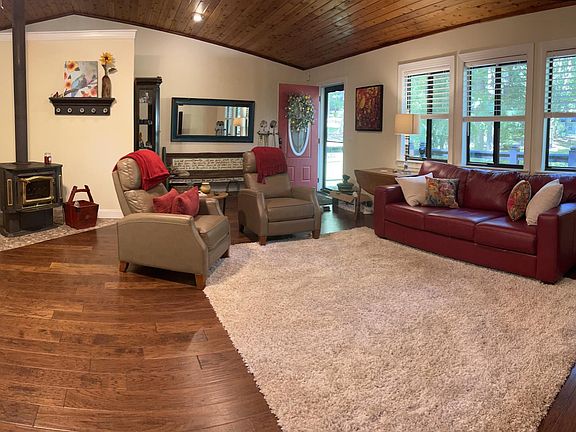 Cozy living space with two recliners, leather sofa and wood-burning stove.
