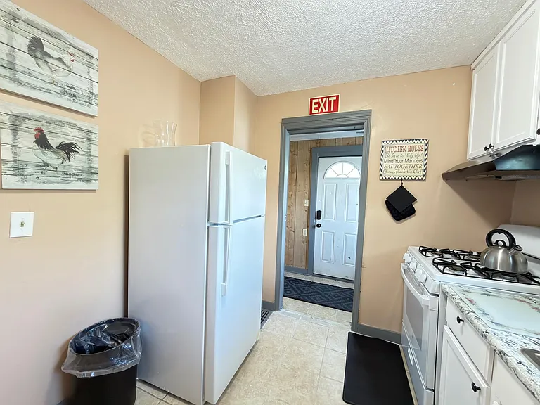 Functional kitchen with full-size refrigerator, gas range, ample cabinetry, and durable tile flooring for easy upkeep.