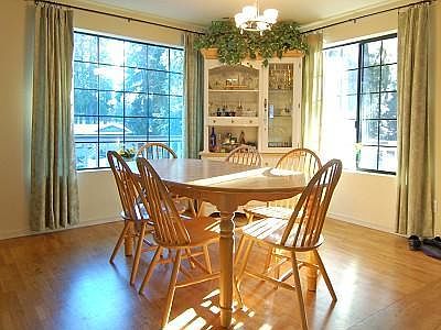 Radiant dining area has gleaming hardwood floor and large picture windows, with an open concept floo