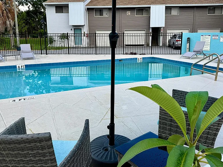 Inviting apartment pool area with comfortable seating, surrounded by modern townhouses, perfect for relaxation and leisure.