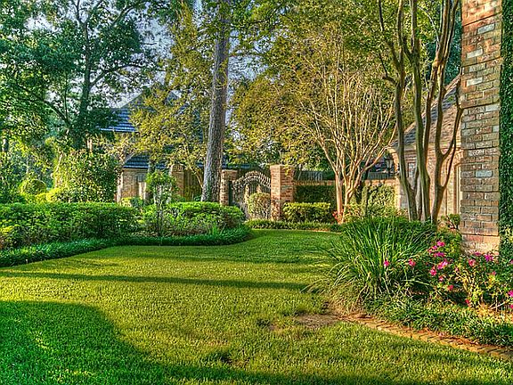 Double lot boasts lush landscaping with mature trees dappling in sunlight.