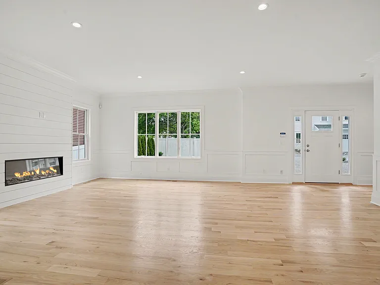 Light Coastal Hardwood Floors, Sun_Filled Rooms, and a Gas Fireplace Define the Home's Bright, Modern Flow.