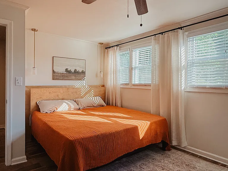 Bright master bedroom with a king bed, ceiling fan, and pendant lights