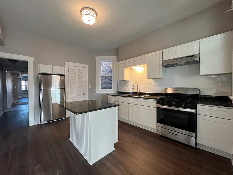 Newly renovated kitchen with granite countertops, crisp white cabinets, brand new stainless steel appliances, food pantry, and island which opens up to the den space.