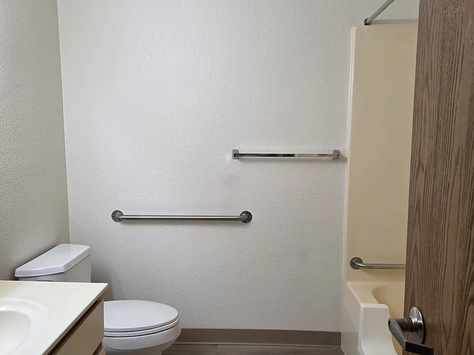Bathroom, complete with grab bars. Some showers have cut out entrance to make it easy for everyone to get in and out of the shower.