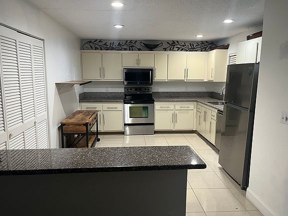 Kitchen with newer appliances and island for barstools