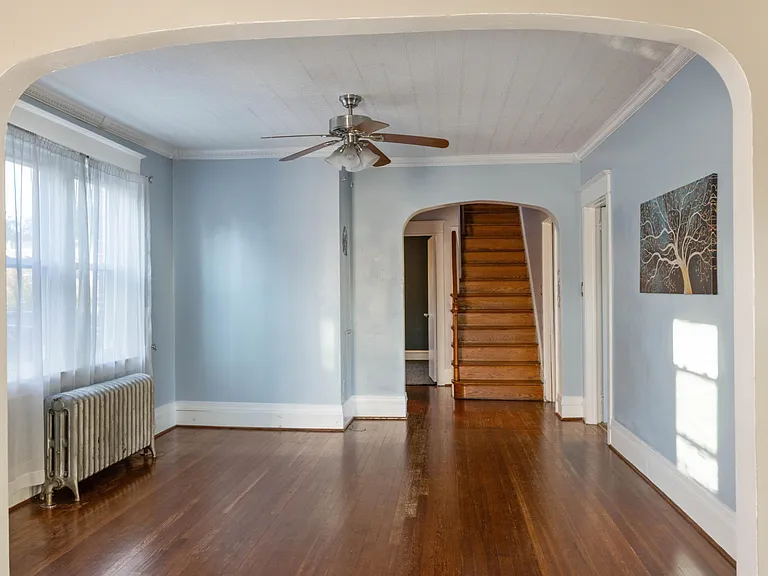 Dining room with hardwood floors and faux tin ceiling. Stairs to 2nd floor in the distance.
