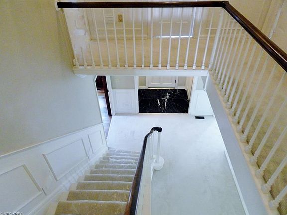 Grand staircase w/wainscoting showing main entry with marble & open center area of 2nd level