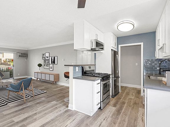 Kitchen with blue tile backsplash and view of adjacent living room.