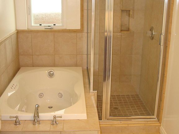 Bathroom with jacuzzi tub and separate shower. Access to bathroom from front bedroom and separate access from living room/kitchen area.
