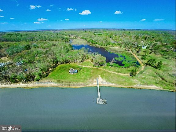 Spectacular overview aerial. Pier, 1940s cabin, marsh are prominent. Main residence is on bluff at edge of marsh, facing the Pot