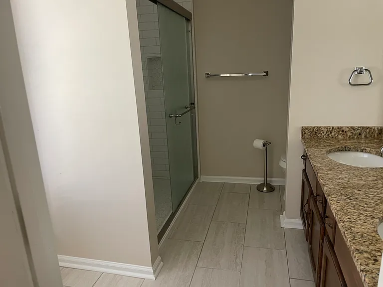 Brand new wood plank style tile flooring in master bathroom along with granite countertops.