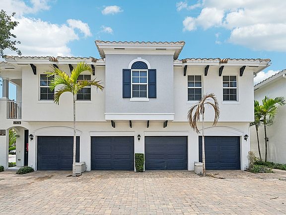 Charming Mediterranean architecture, featuring a tiled roof and vibrant palm trees, offering spacious two-car garages.