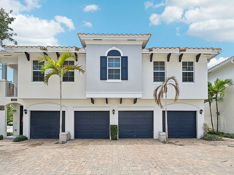 Charming Mediterranean architecture, featuring a tiled roof and vibrant palm trees, offering spacious two-car garages.