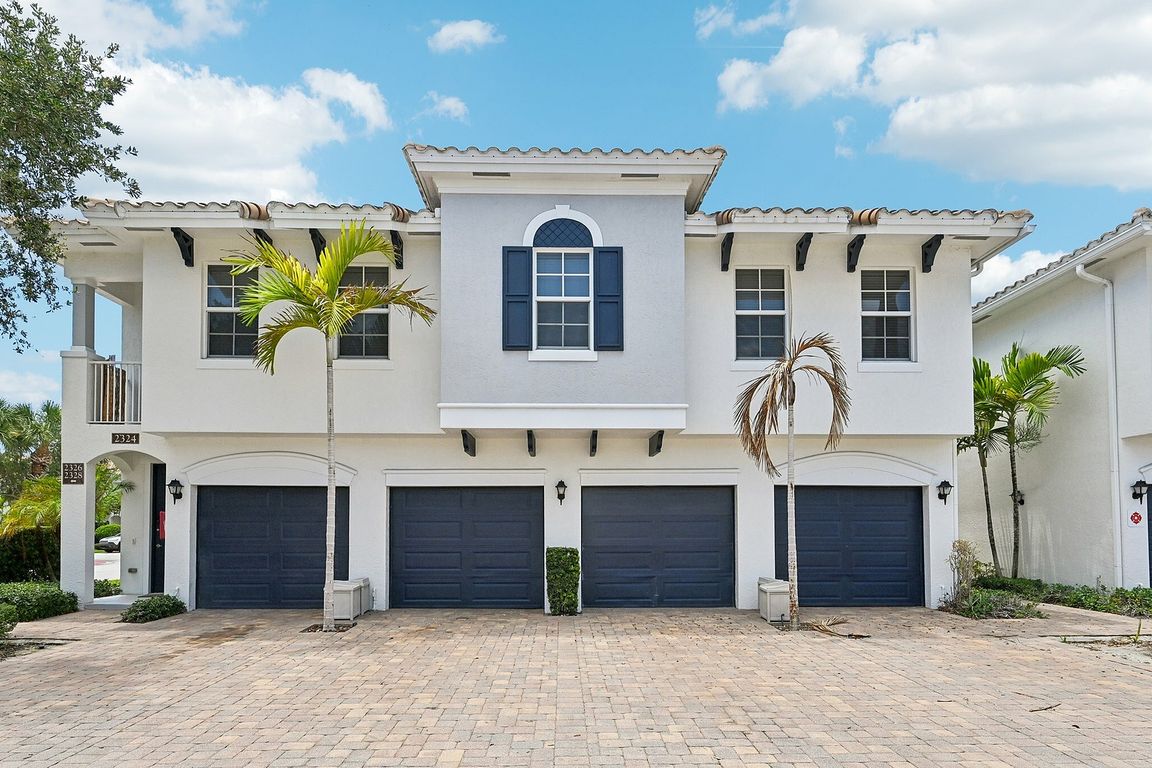 Charming Mediterranean architecture, featuring a tiled roof and vibrant palm trees, offering spacious two-car garages.