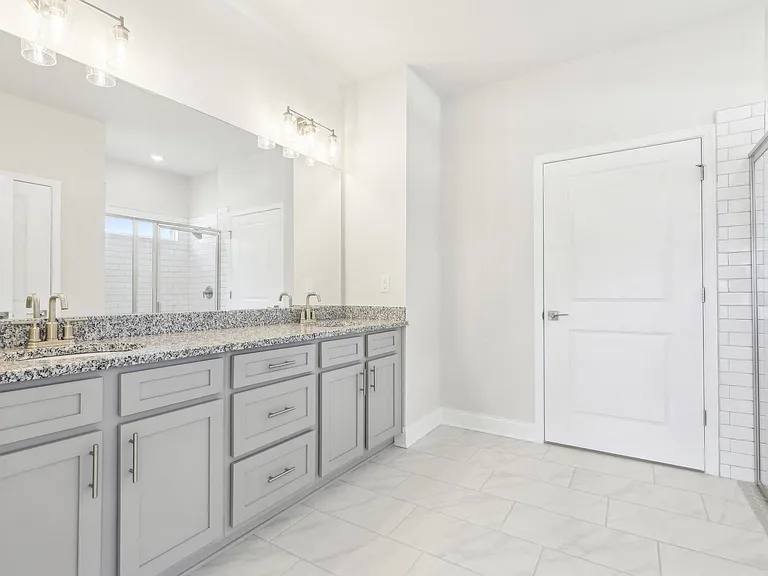 Luxurious primary bathroom featuring a double vanity, walk-in shower, and spacious walk-in closet.