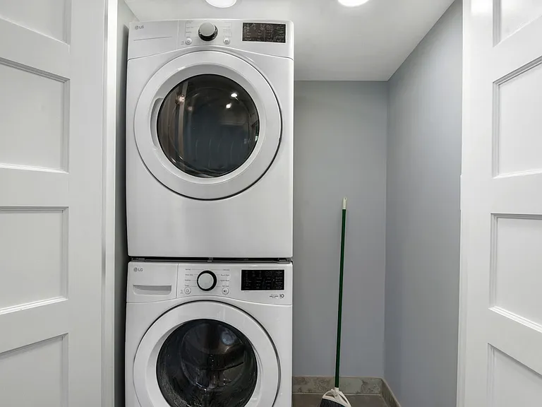 bedroom level laundry room with full size stack washer and dryer with area for cleaning supplies and equipment