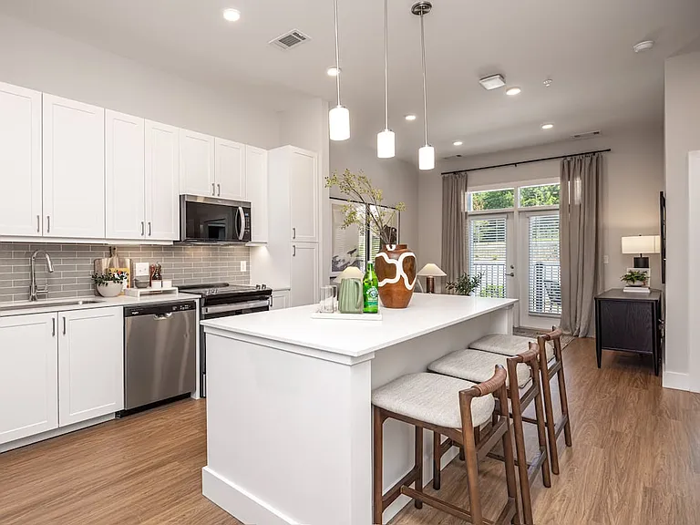 Modern kitchen with white cabinetry, undercabinet lighting, grey tile backsplash, and white quartz countertops