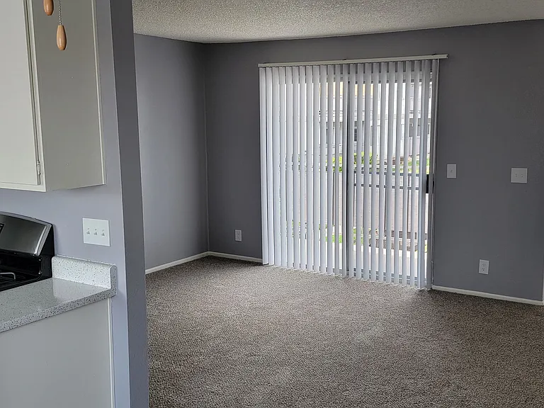 Enterance, carpeted living room and kitchen at Grand Oaks Apartments in Lake Elsinore, California.