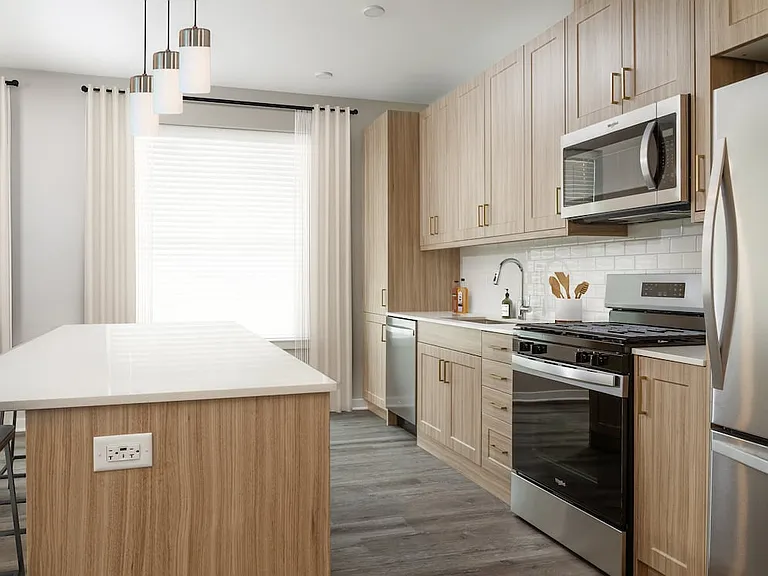 Base Collection kitchen with stainless steel appliances, quartz countertops, tile backsplash, oak cabinetry, and hard-surface flooring