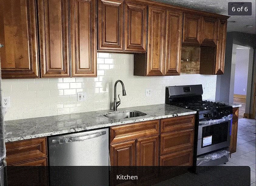 Kitchen with granite countertops, gas stove, diswasher and fridge.