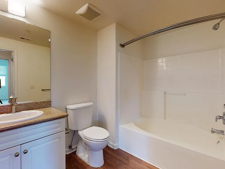 Apartment bathroom with large soaking tub and wood-style flooring.