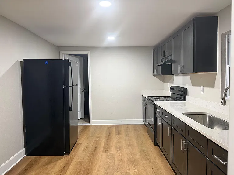 Updated kitchen with dark cabinetry, ample counter space, stainless sink, and full-size appliances for easy meal prep.
