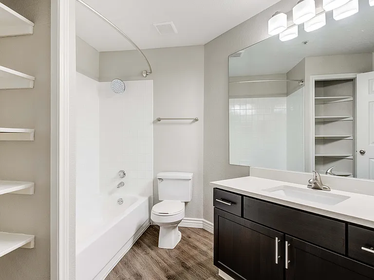 Modern bathroom featuring elegant dark wood cabinetry, a spacious mirror, and sleek fixtures complemented by clean white tiles.