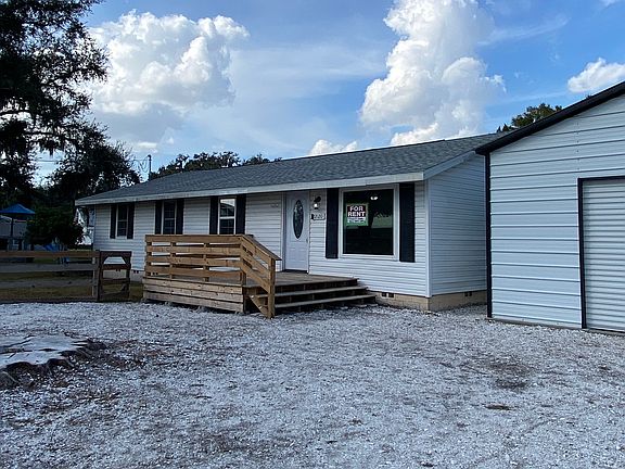 Front exterior with fenced yard, large gravel driveway, large front deck, and detached barn garage