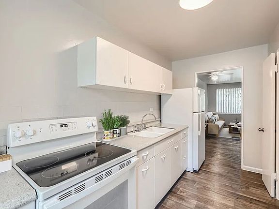 A white kitchen with a stove, sink, and cabinets.