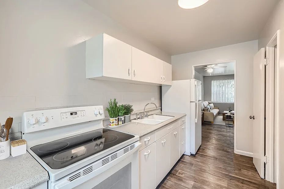 A white kitchen with a stove, sink, and cabinets.