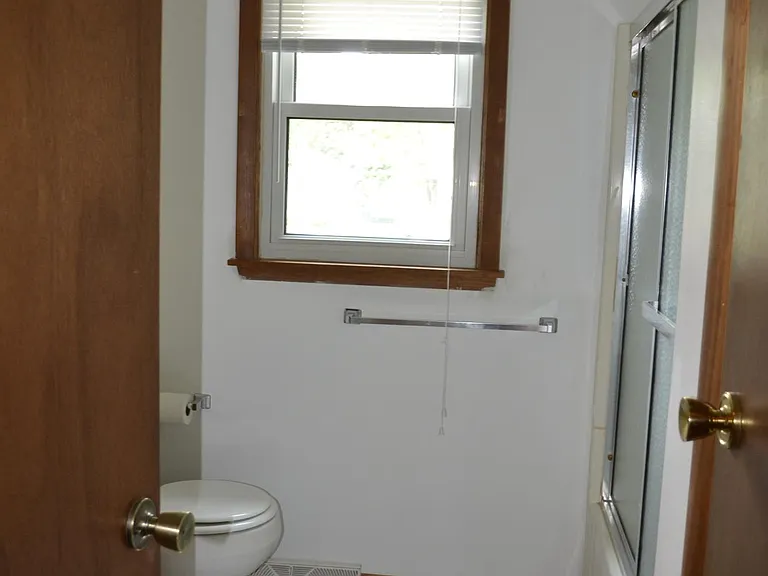 Bathroom has a shower/tub with sliding doors, toilet and vanity. Window looks out at back yard. Storage closet in bathroom.