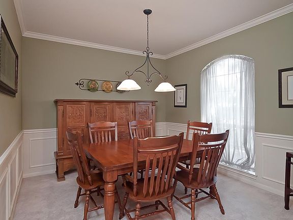 This large dining room features crown molding, wainscoating, and decorator paint.
