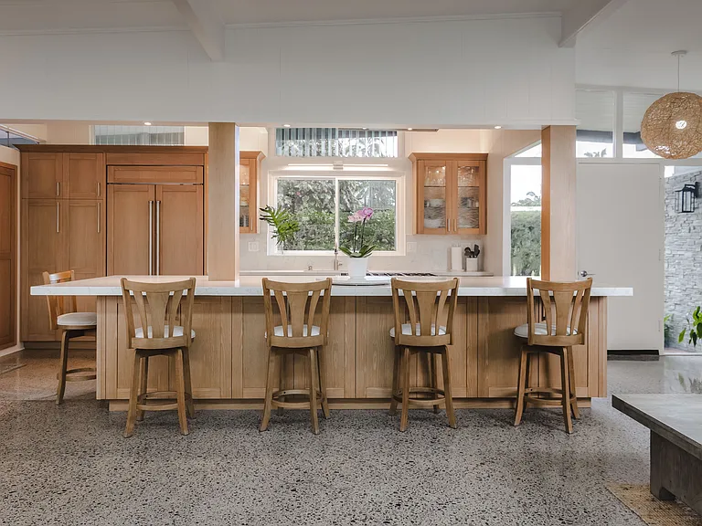 Open new kitchen with large island with quartz countertops and top-end appliances.